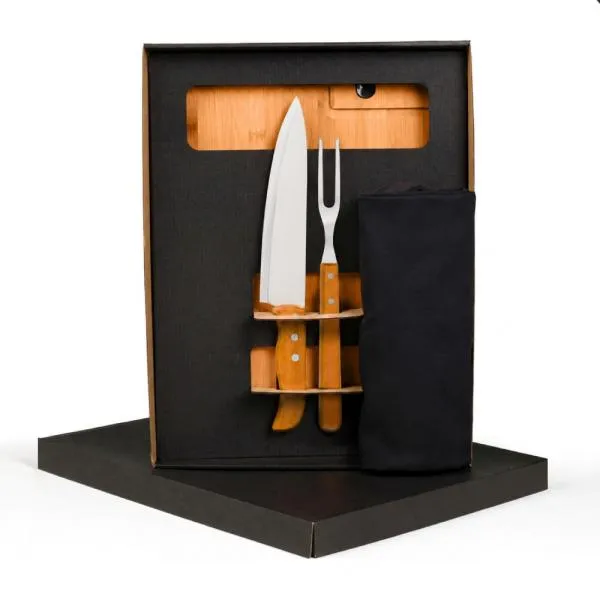 Conjunto para Churrasco. Composto por tábua em Bambu e amolador embutido na tábua; faca 8 e garfo trinchante em Madeira/Inox. Conta também com avental em Brim Preto.